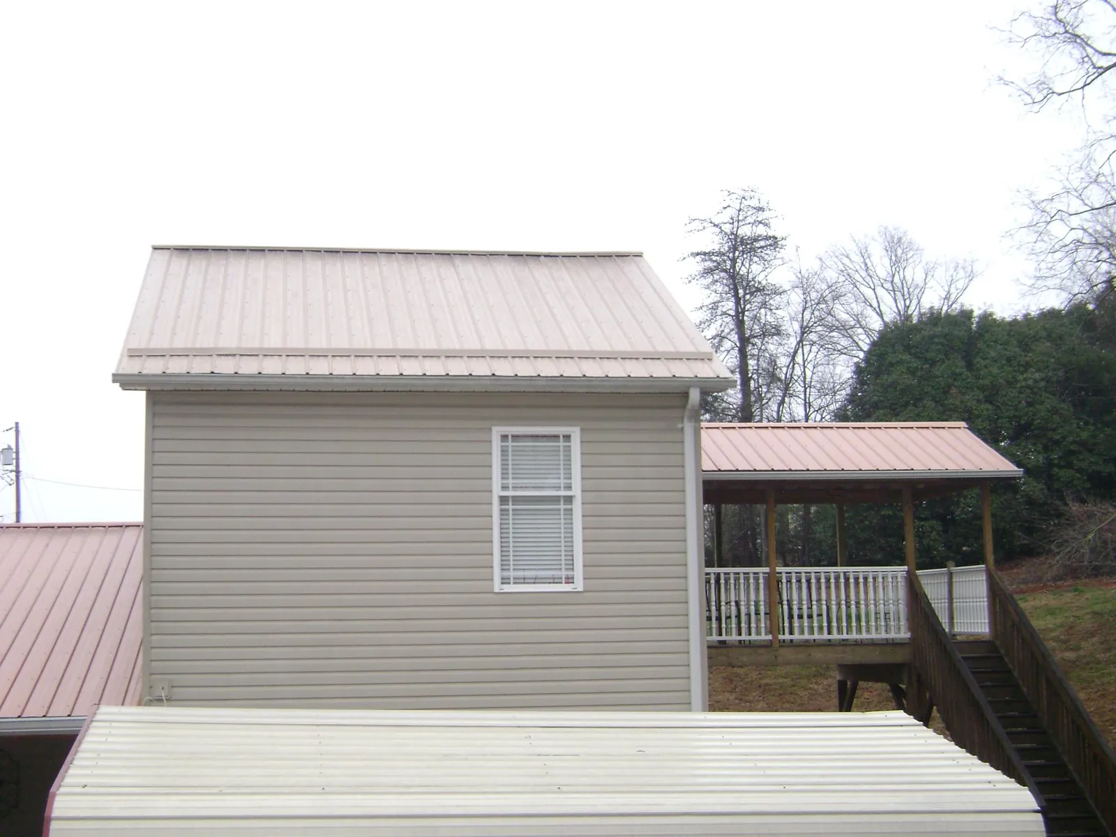 Tan metal roofs on a two story addition and attached porch, from a Roof Replacement job in Somerville